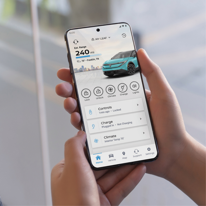 Two hands hold a smartphone displaying the NissanConnect EV app. The app shows Est. Range 240 mi and controls for a Nissan Leaf.